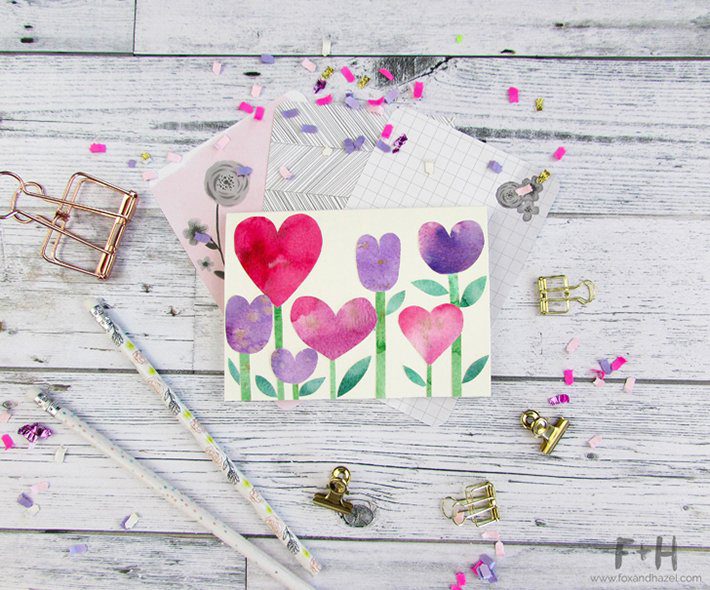 watercolor heart shaped flowers on white card on wood background