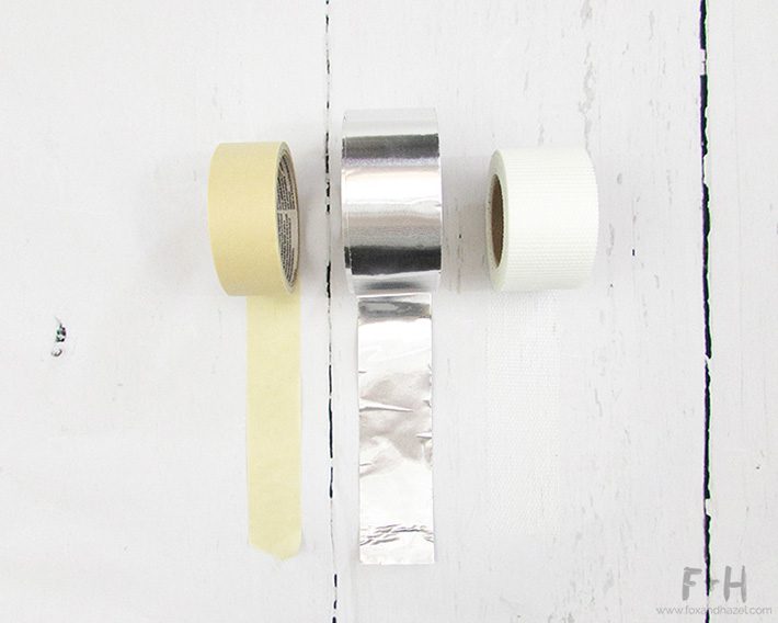 rolls of masking tape, metal duct tape and drywall joint tape on white background