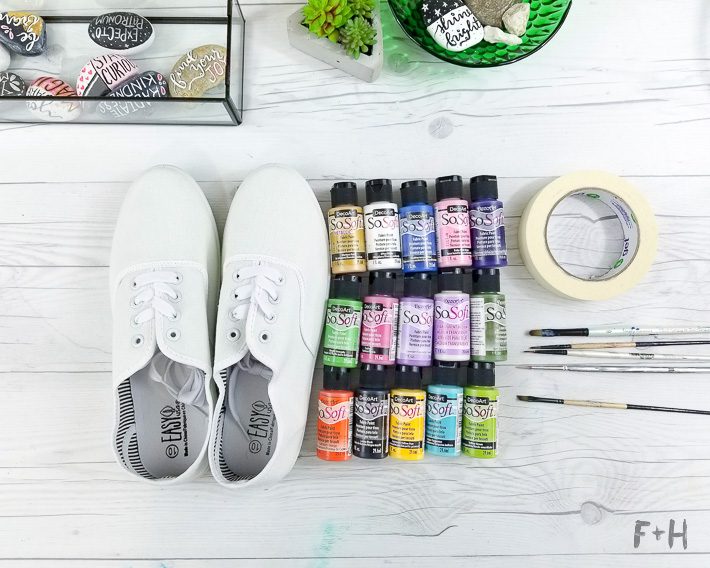 white canvas sneakers next to paint bottles