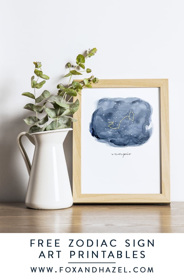 zodiac signs art in frame next to white vase with eucalyptus leaves