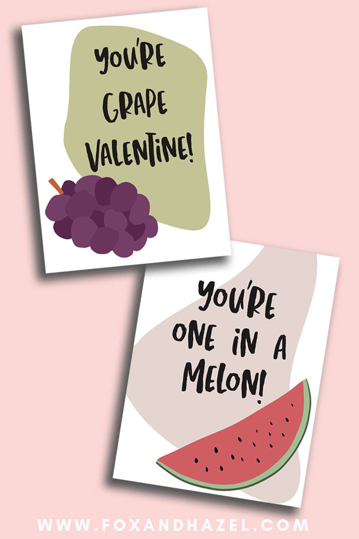 Two fruit Valentine's Day cards lay on a pink background. One card has grapes and reads "You're grape, Valentine!" The second card has a slice of watermelon and reads "You're one in a melon!"